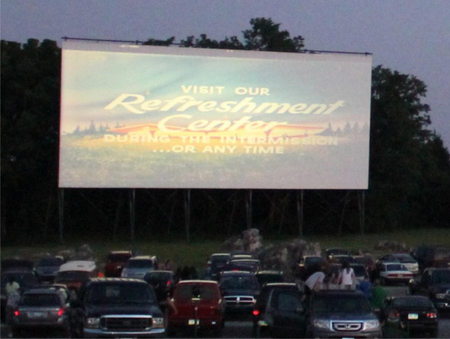 Cars line up and wait for a movie to start at a drive-in theater
