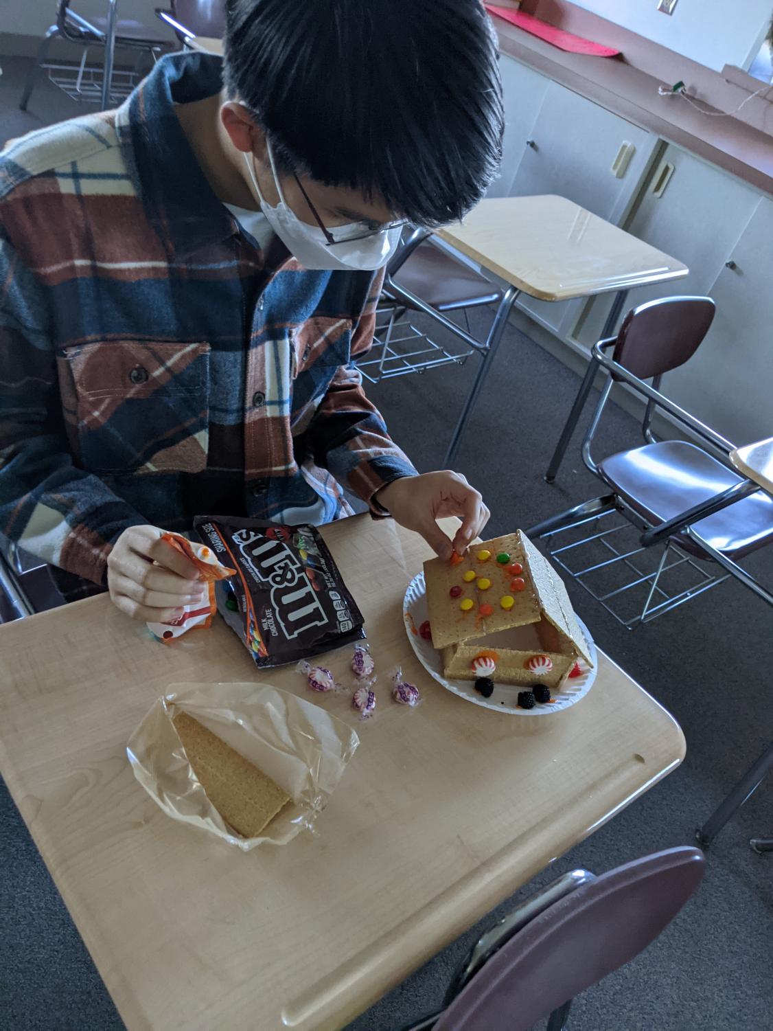 Photo Credit: Jennifer Ibanez
Junior James Kim adds candy decorations to the roof of a carefully created lebkuchenhaus (traditional German Gingerbread house) during the German Club meeting on Dec. 6. Photo courtesy of Jennifer Ibanez 
