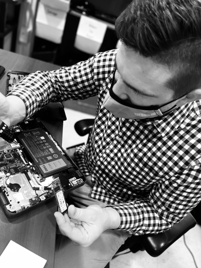 Technology support specialist Tim Gunier replaces the hard drive on a student's broken laptop. Photo by Alex Eydenberg