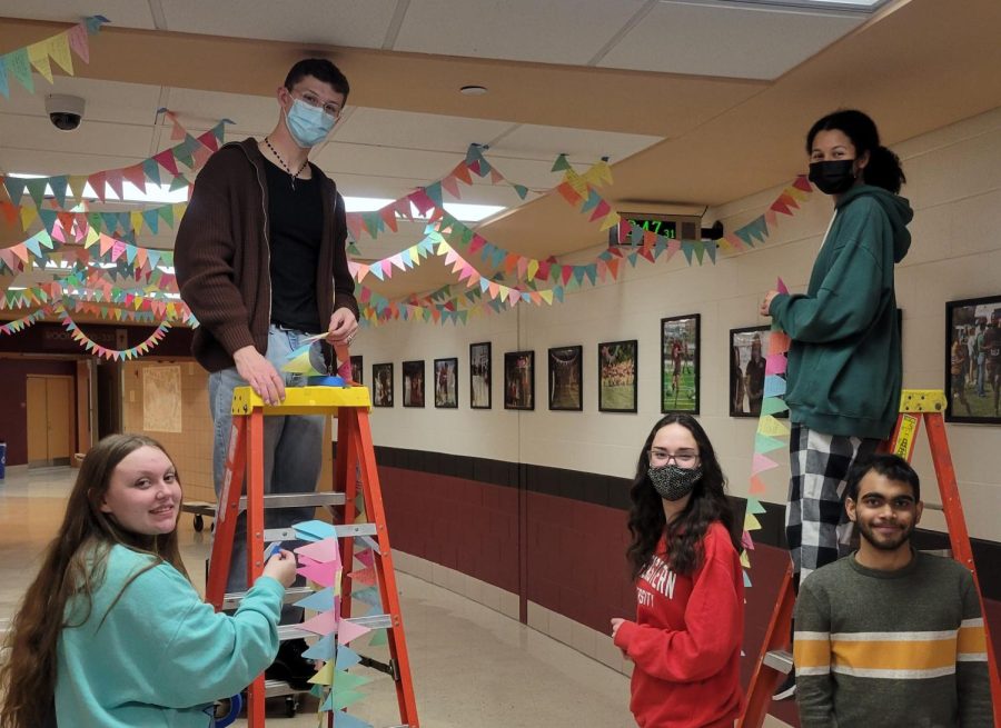 Junior Olivia Zary, senior Alex Chartrand, junior Allison Smith, and seniors Mary Henry and Siddarth Durai hang hallway banners as decoration. Photo by Lara Hannemann