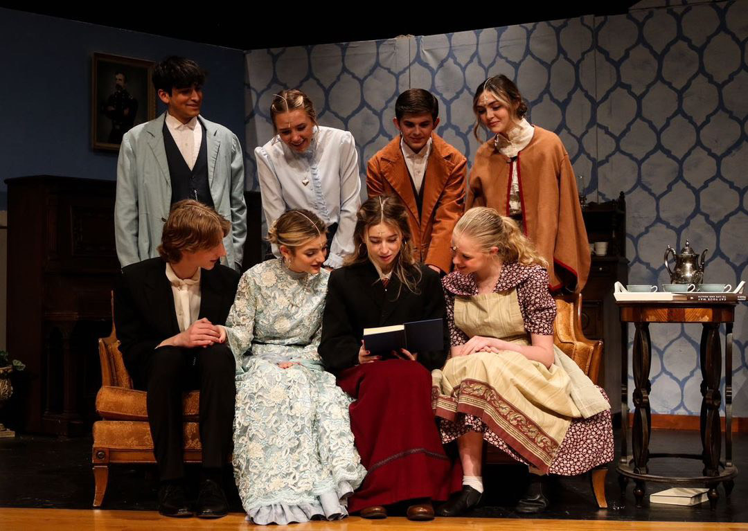 The cast of “Little Women” gathers around Jo March, played by junior Addison Kyrychenko, as she displays her first published novel. 