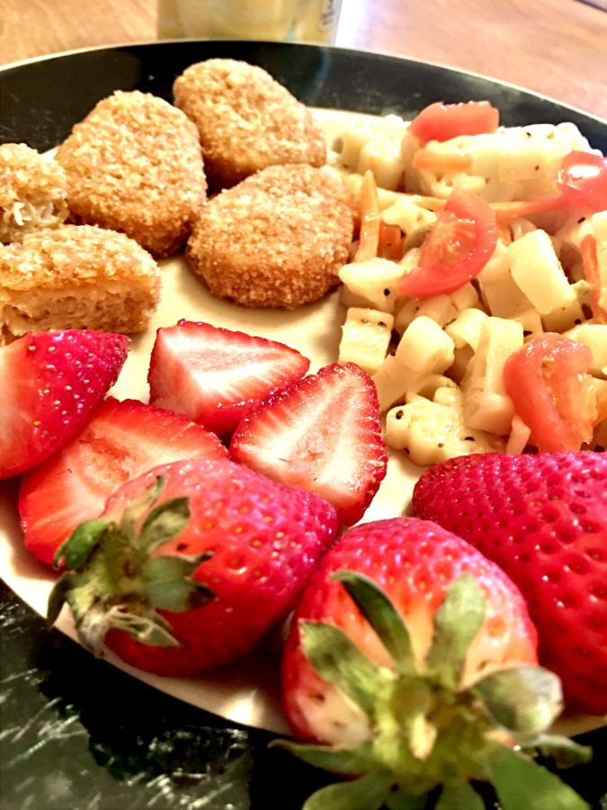 Vegan meal consisting of strawberries, vegan "chicken" nuggets and pasta with a vinaigrette dressing
