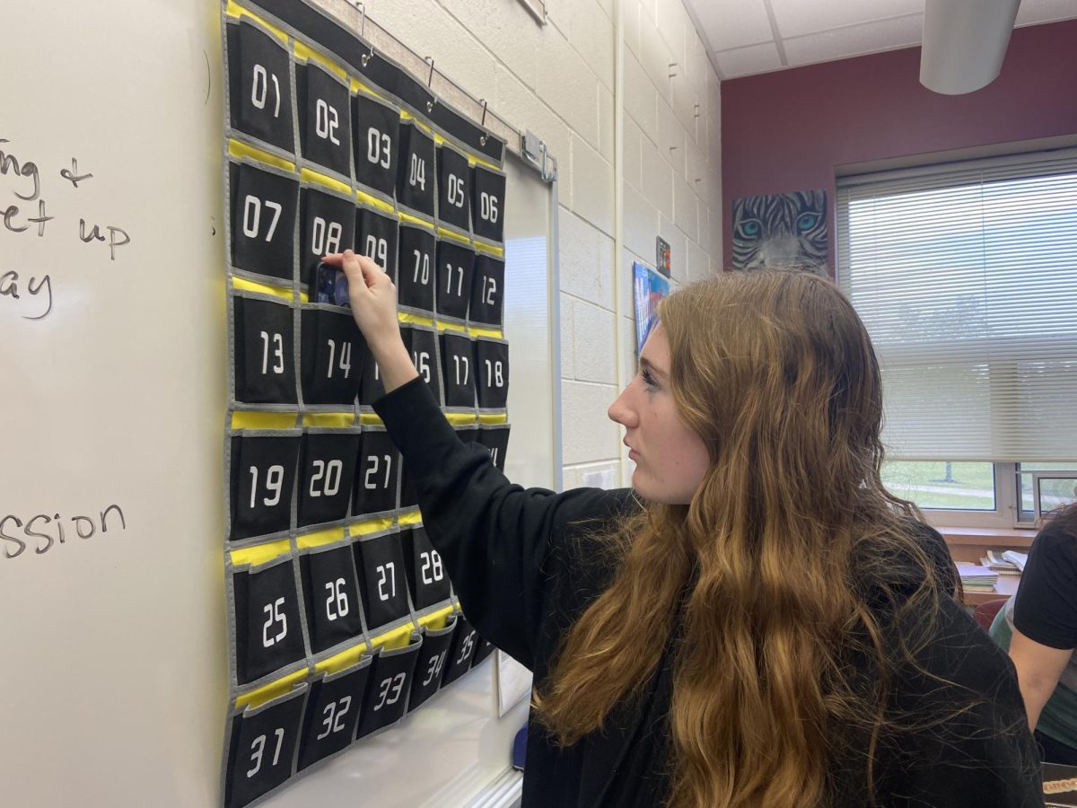 Senior Abby Nelson places her phone in one of the holders in accordance with new policy.